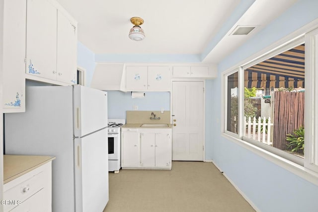 kitchen with a sink, white appliances, and white cabinets