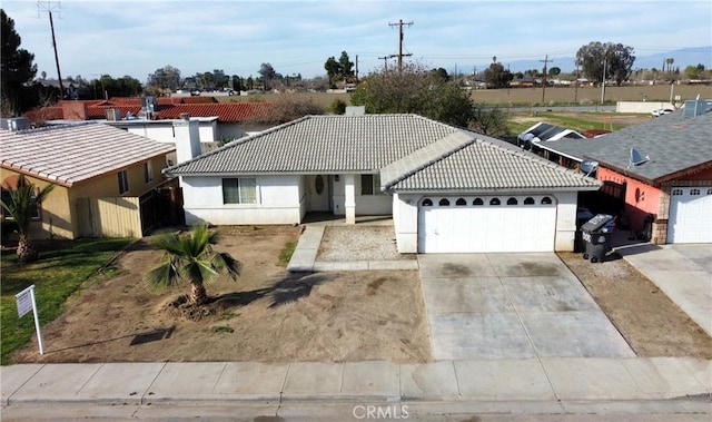 single story home featuring stucco siding, concrete driveway, an attached garage, and a tile roof