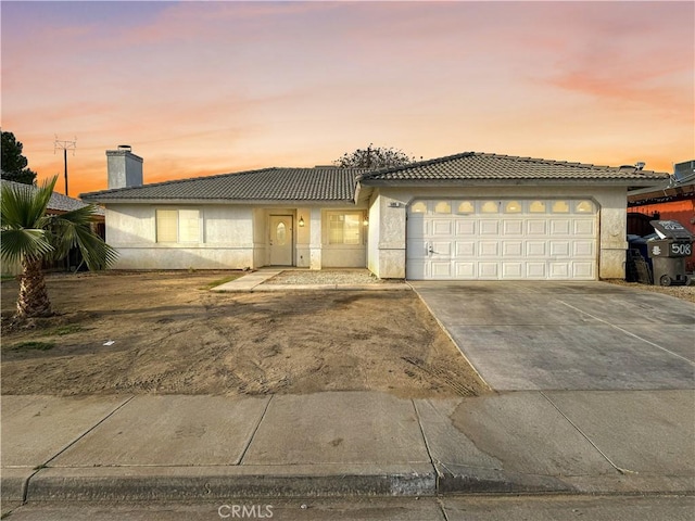 view of front facade with stucco siding, a garage, concrete driveway, and a tiled roof