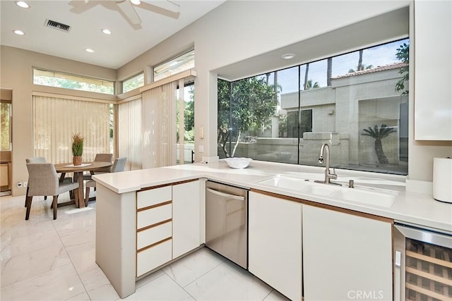 kitchen featuring marble finish floor, beverage cooler, a sink, stainless steel dishwasher, and white cabinetry