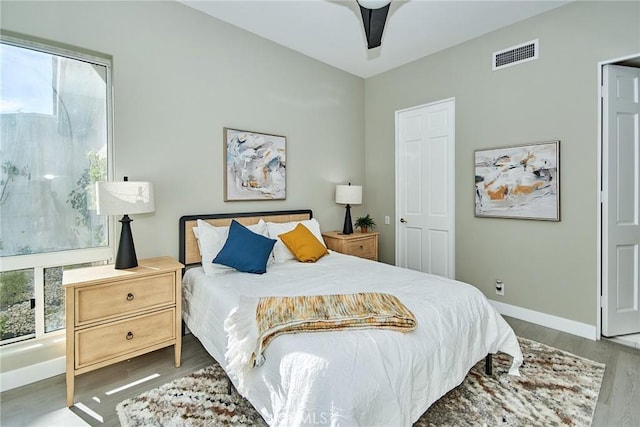 bedroom featuring ceiling fan, visible vents, baseboards, and wood finished floors