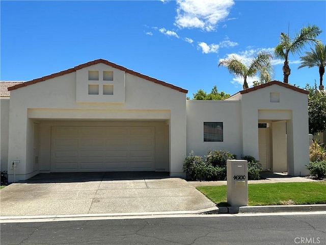 view of front of house with a garage, concrete driveway, and stucco siding