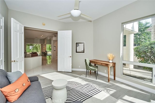 living area with a ceiling fan, baseboards, and a wealth of natural light