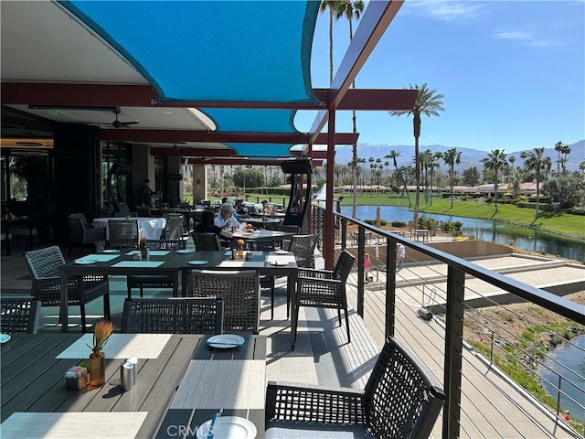 wooden deck with a water view and outdoor dining space