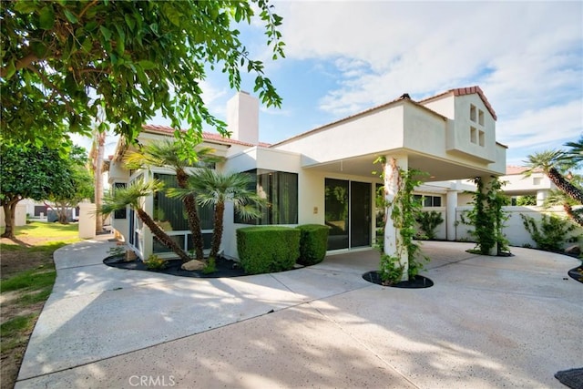 mediterranean / spanish house with stucco siding, driveway, and a chimney