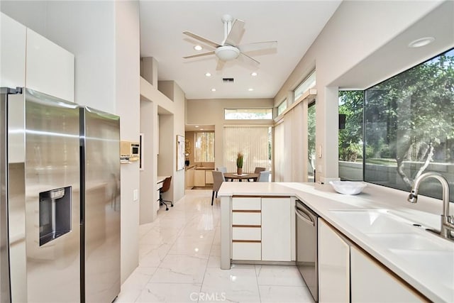 kitchen with marble finish floor, a sink, appliances with stainless steel finishes, white cabinets, and light countertops