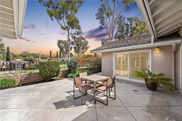 patio terrace at dusk with outdoor dining area and fence