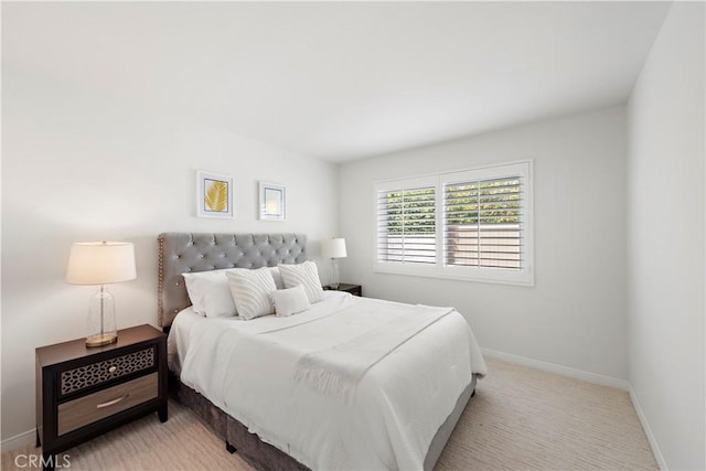 bedroom featuring light colored carpet and baseboards