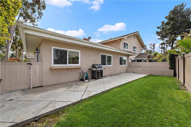 rear view of property featuring a yard, a patio area, stucco siding, and a fenced backyard