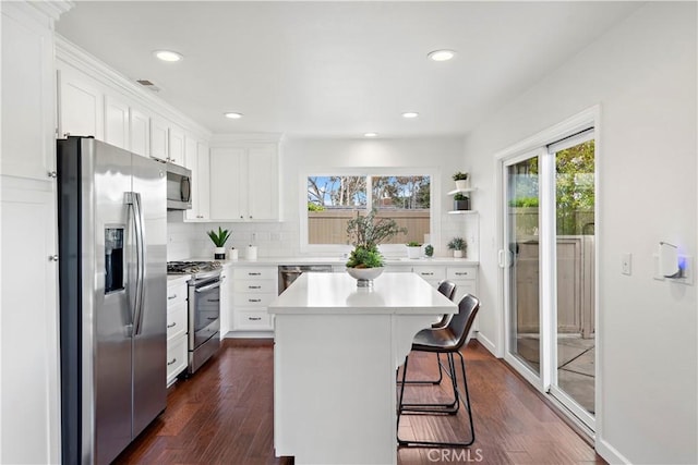 kitchen featuring a breakfast bar area, stainless steel appliances, light countertops, white cabinets, and tasteful backsplash