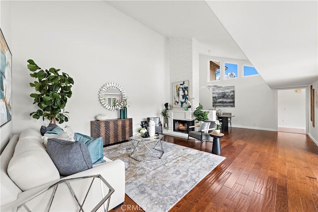 living room with wood finished floors, a fireplace, baseboards, and high vaulted ceiling