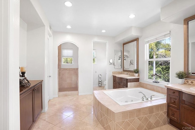 bathroom with recessed lighting, a whirlpool tub, plenty of natural light, and tile patterned flooring