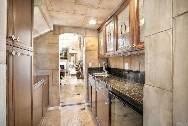 kitchen featuring wine cooler, a sink, glass insert cabinets, tile counters, and a fireplace