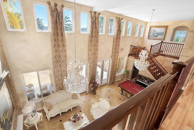 interior space with a chandelier, a healthy amount of sunlight, and beamed ceiling
