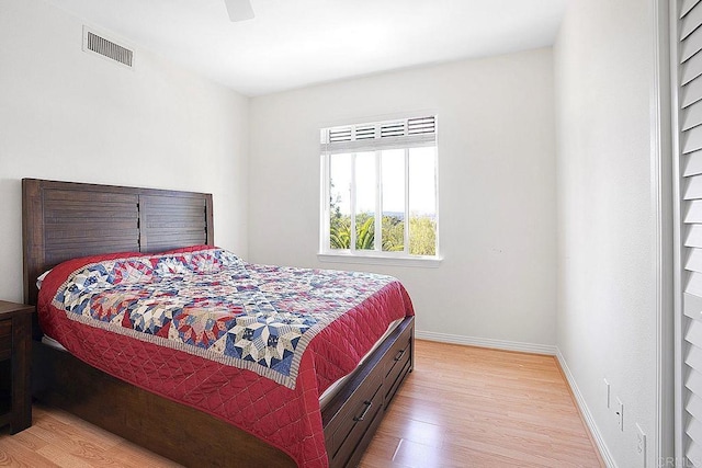bedroom with baseboards, a ceiling fan, wood finished floors, and visible vents