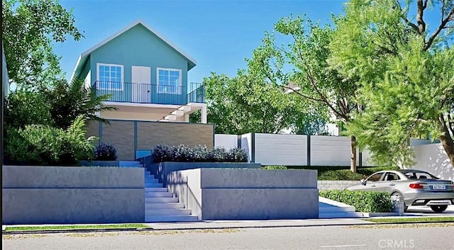 view of front of property featuring stucco siding, stairs, and fence