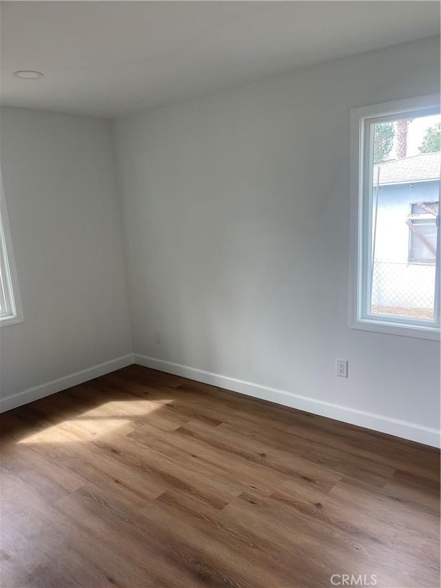 spare room featuring baseboards and wood finished floors