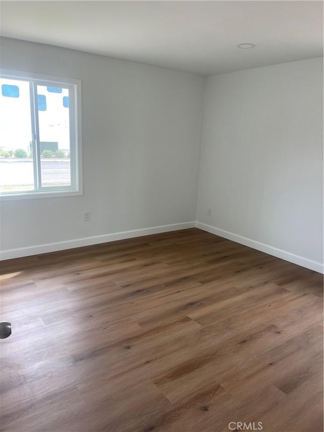 unfurnished room with baseboards and wood finished floors