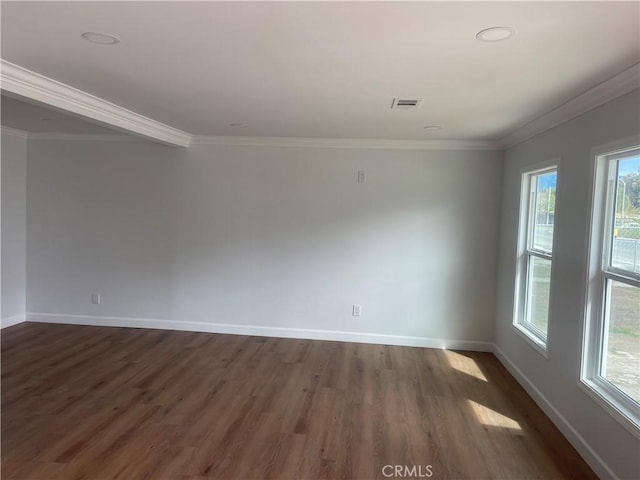 spare room featuring crown molding, baseboards, visible vents, and dark wood-style flooring