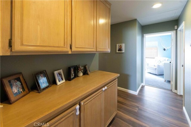 corridor with baseboards and dark wood-type flooring