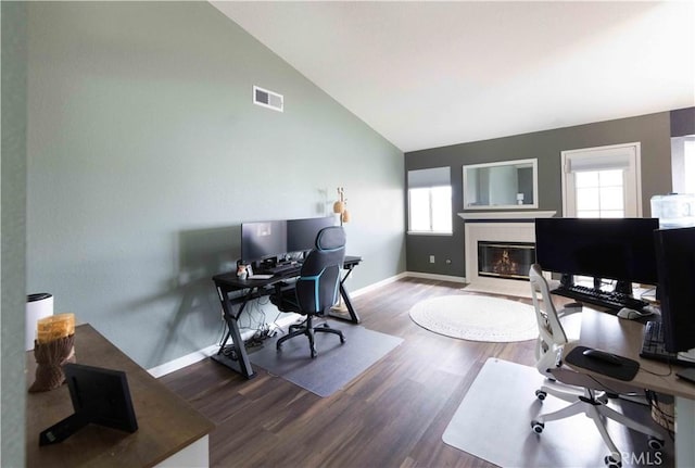 office with visible vents, high vaulted ceiling, wood finished floors, a fireplace, and baseboards