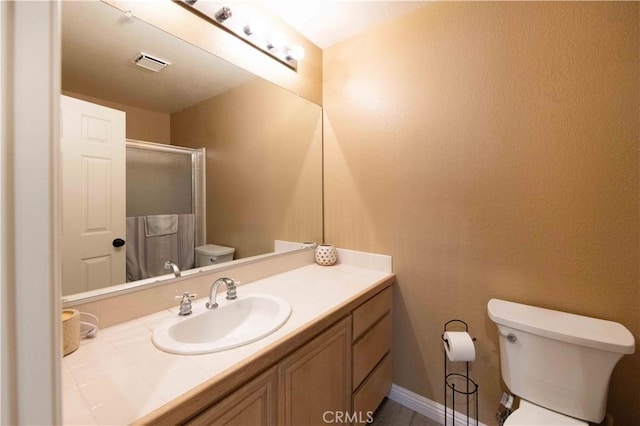 bathroom with visible vents, a shower stall, baseboards, toilet, and vanity