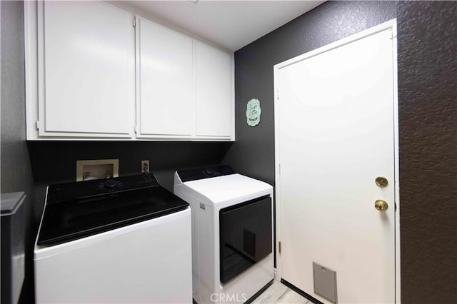 clothes washing area with cabinet space, independent washer and dryer, and a textured wall