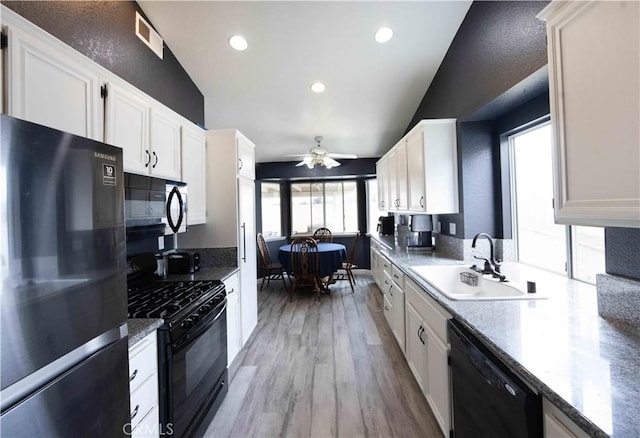 kitchen with light wood finished floors, visible vents, black appliances, white cabinetry, and a sink