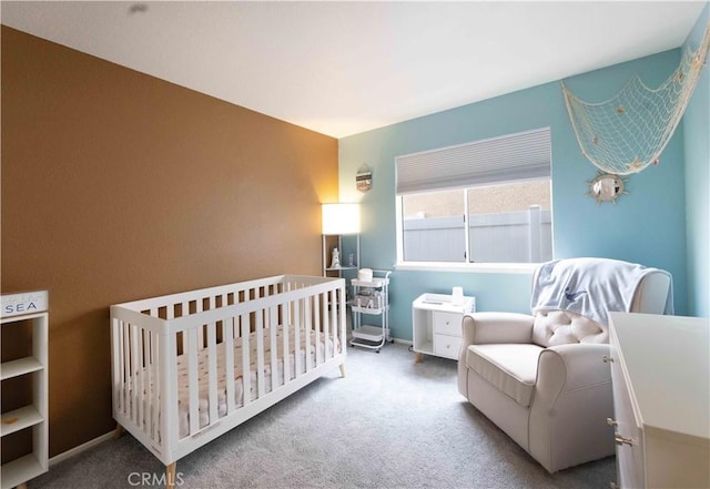 carpeted bedroom featuring a crib and baseboards