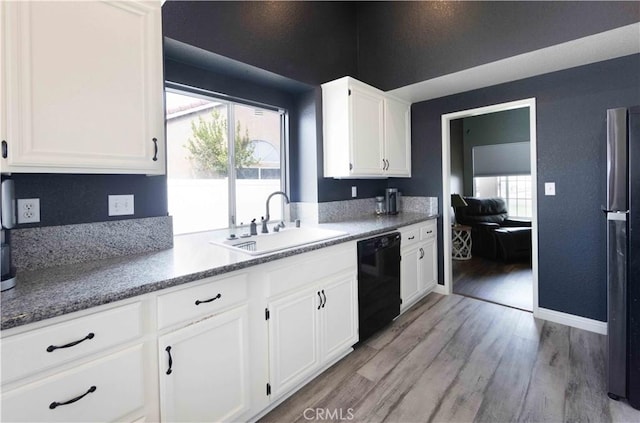 kitchen with light wood finished floors, a healthy amount of sunlight, dishwasher, freestanding refrigerator, and a sink