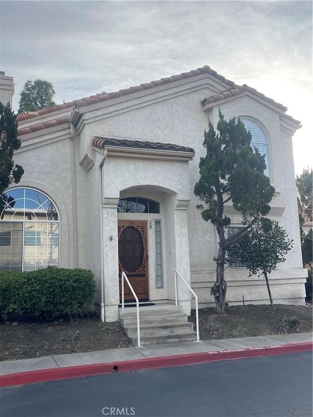 mediterranean / spanish house featuring stucco siding and a tiled roof