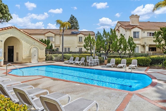 pool with a patio area, a residential view, and fence