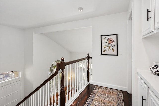 corridor with baseboards, an upstairs landing, dark wood-style flooring, and vaulted ceiling