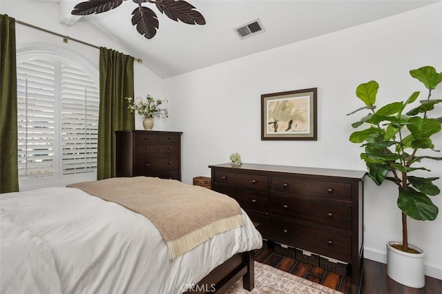 bedroom with visible vents, baseboards, dark wood-style floors, and vaulted ceiling