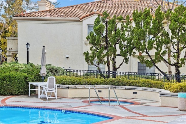 community pool with a patio, an in ground hot tub, and fence