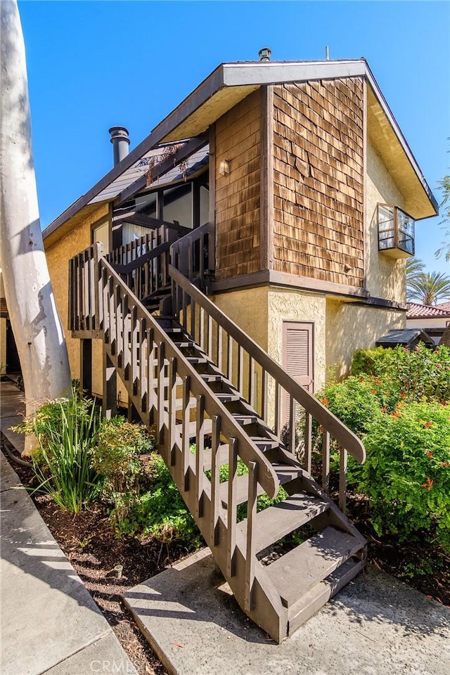 view of side of property featuring stairway and stucco siding