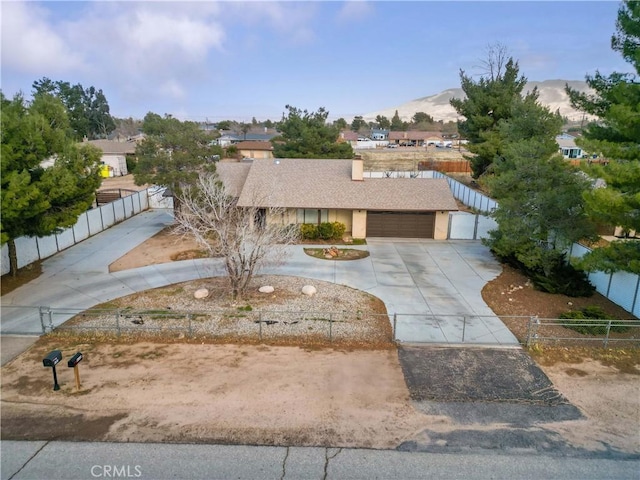 view of front facade featuring a fenced front yard, concrete driveway, roof with shingles, a garage, and a mountain view