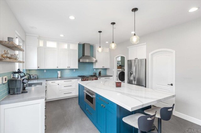 1905 Oxford Ct, Vista, CA 92081 - kitchen featuring appliances with stainless steel finishes, wall chimney exhaust hood, washer / clothes dryer, a center island, and open shelves