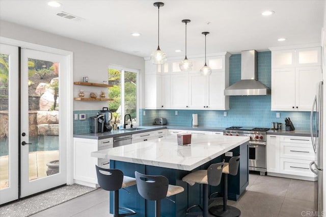 1905 Oxford Ct, Vista, CA 92081 - kitchen featuring wall chimney range hood, stainless steel appliances, decorative backsplash, a center island, and white cabinetry