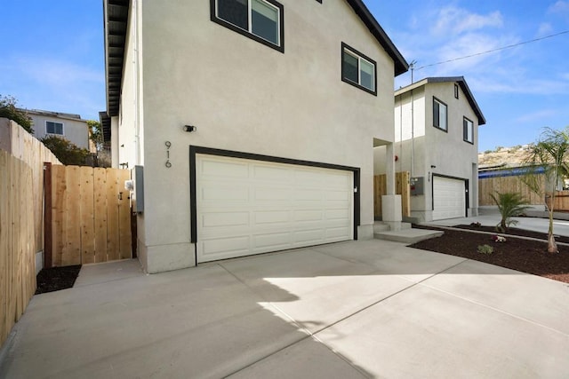 exterior space featuring fence, a garage, and stucco siding