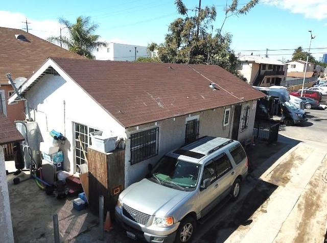 view of front facade featuring roof with shingles and stucco siding