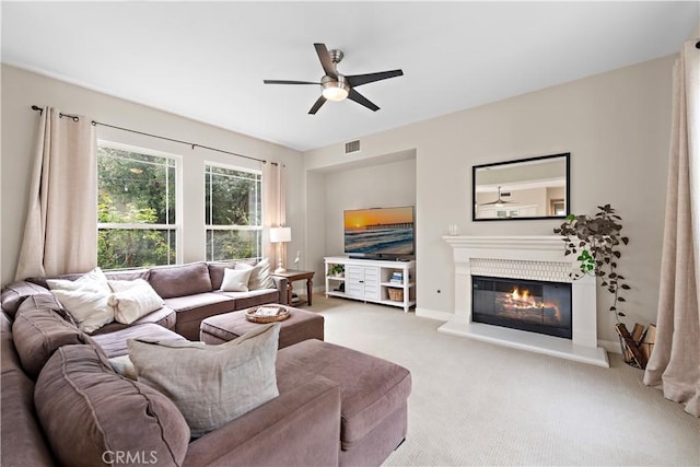 carpeted living area featuring visible vents, baseboards, ceiling fan, and a glass covered fireplace