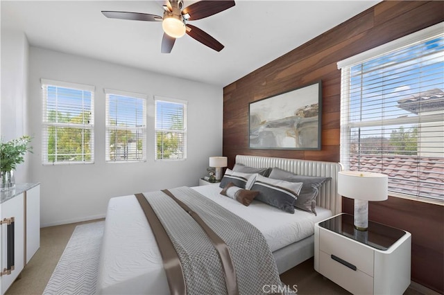 carpeted bedroom with wood walls and a ceiling fan