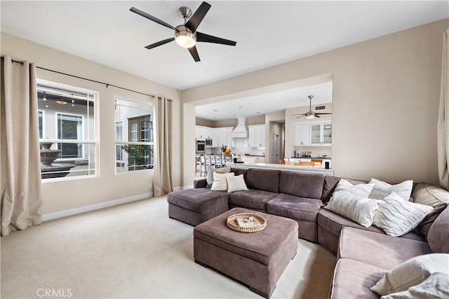 living room featuring light colored carpet, baseboards, and ceiling fan