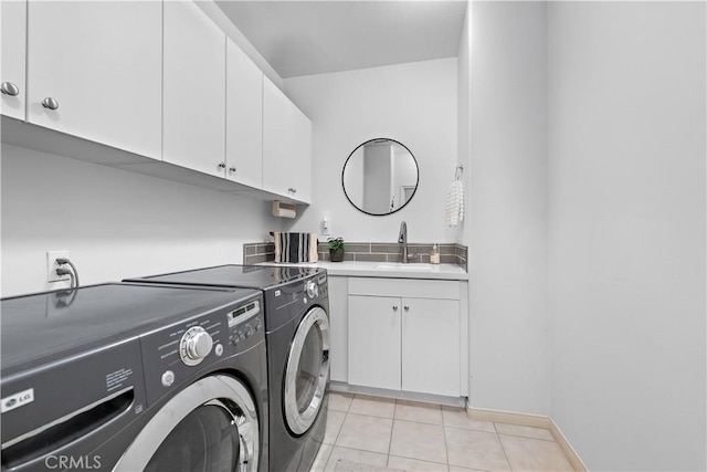 clothes washing area featuring cabinet space, light tile patterned floors, washer and dryer, and a sink