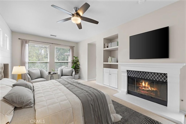 bedroom with visible vents, light colored carpet, a tile fireplace, and a ceiling fan