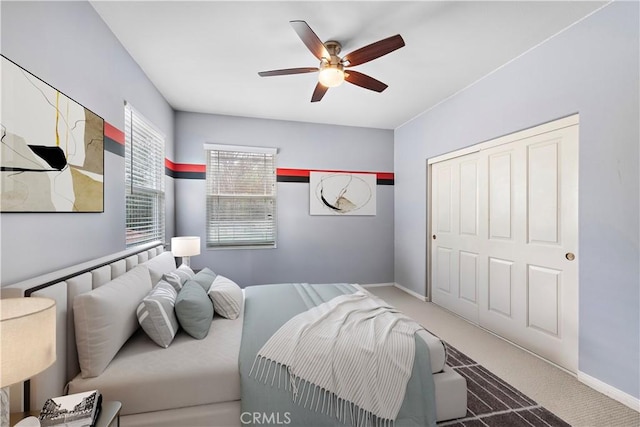 carpeted bedroom featuring a closet, ceiling fan, and baseboards