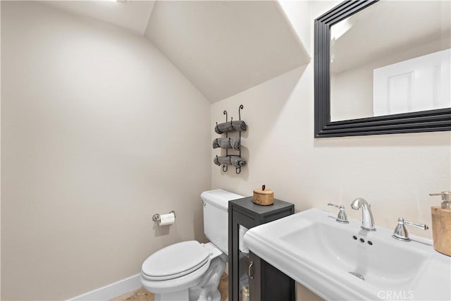 bathroom with a sink, baseboards, lofted ceiling, and toilet