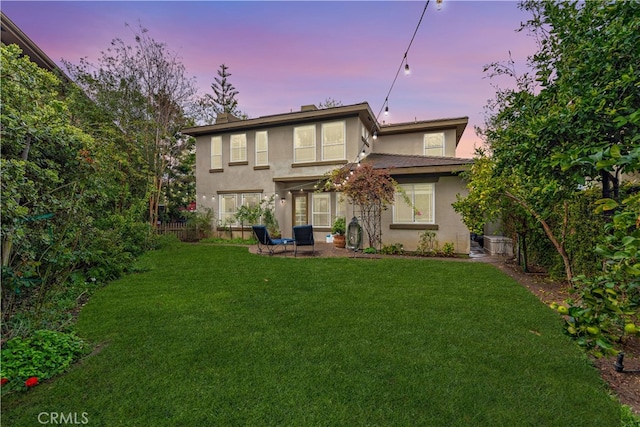 back of property featuring a patio area, stucco siding, and a lawn