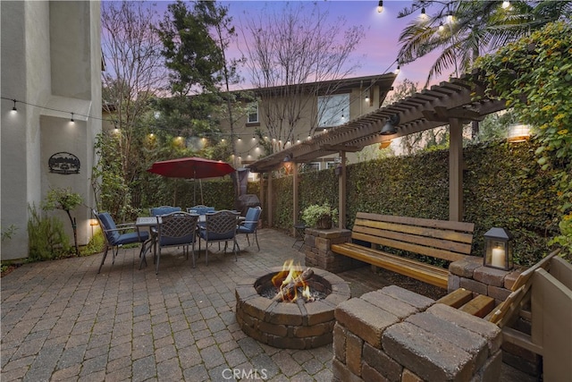 patio terrace at dusk featuring outdoor dining area, fence, a pergola, and an outdoor fire pit